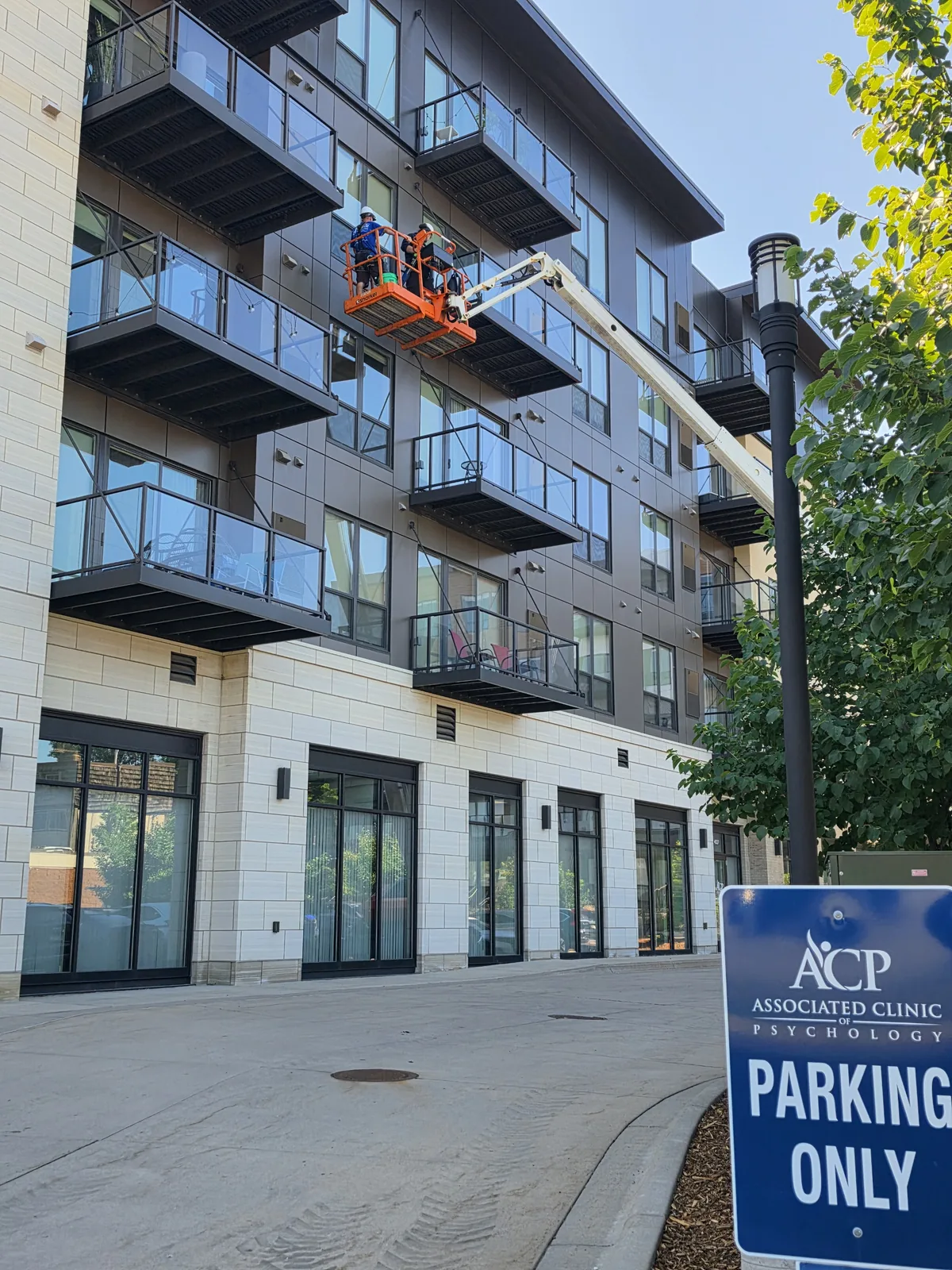 Starbrite Window Cleaning crew in a boom lift cleaning upper-floor windows and balcony glass on a Twin Cities apartment building