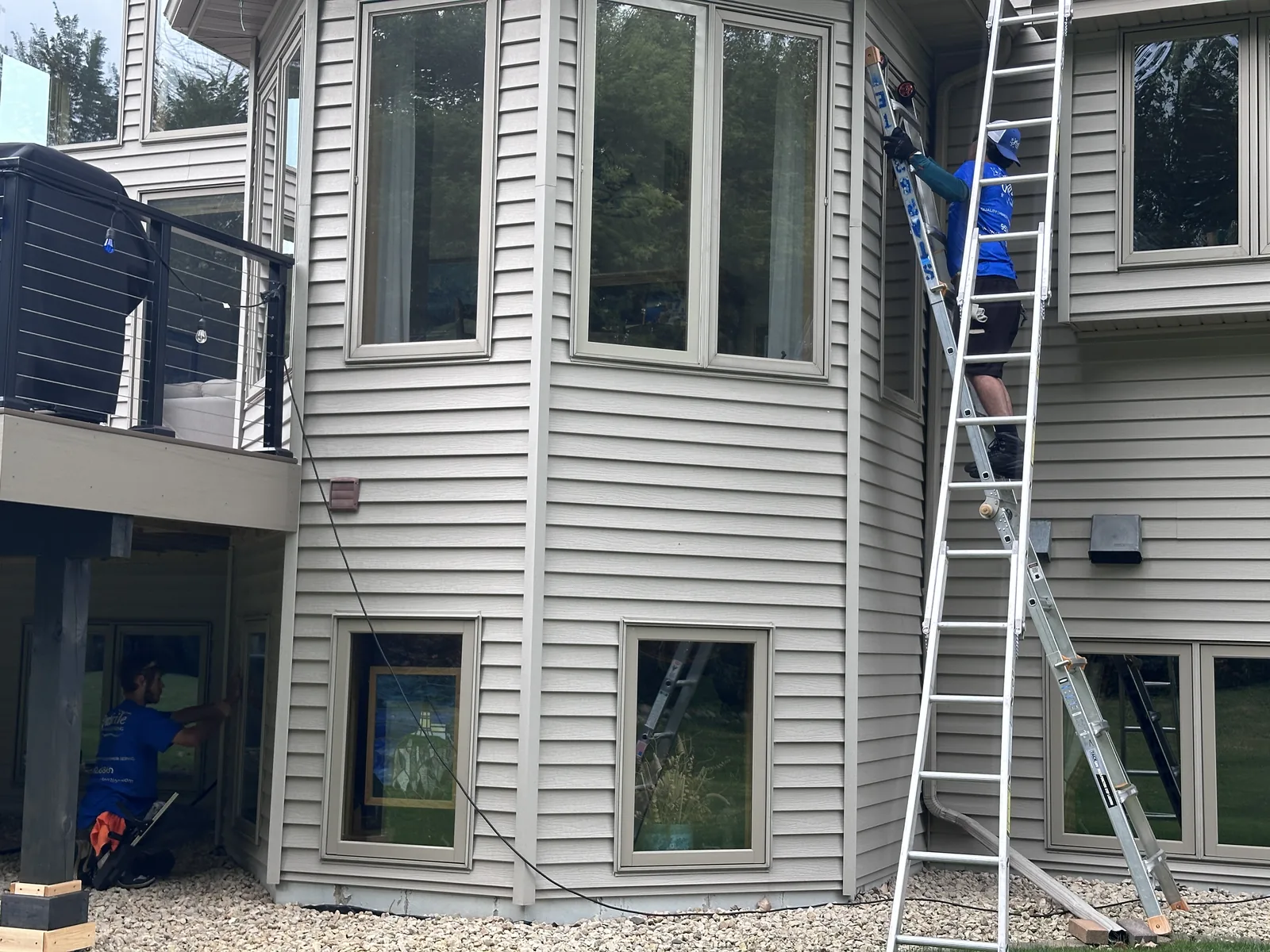 Starbrite Window Cleaning technicians cleaning exterior windows on a two-story Twin Cities home from extension ladders
