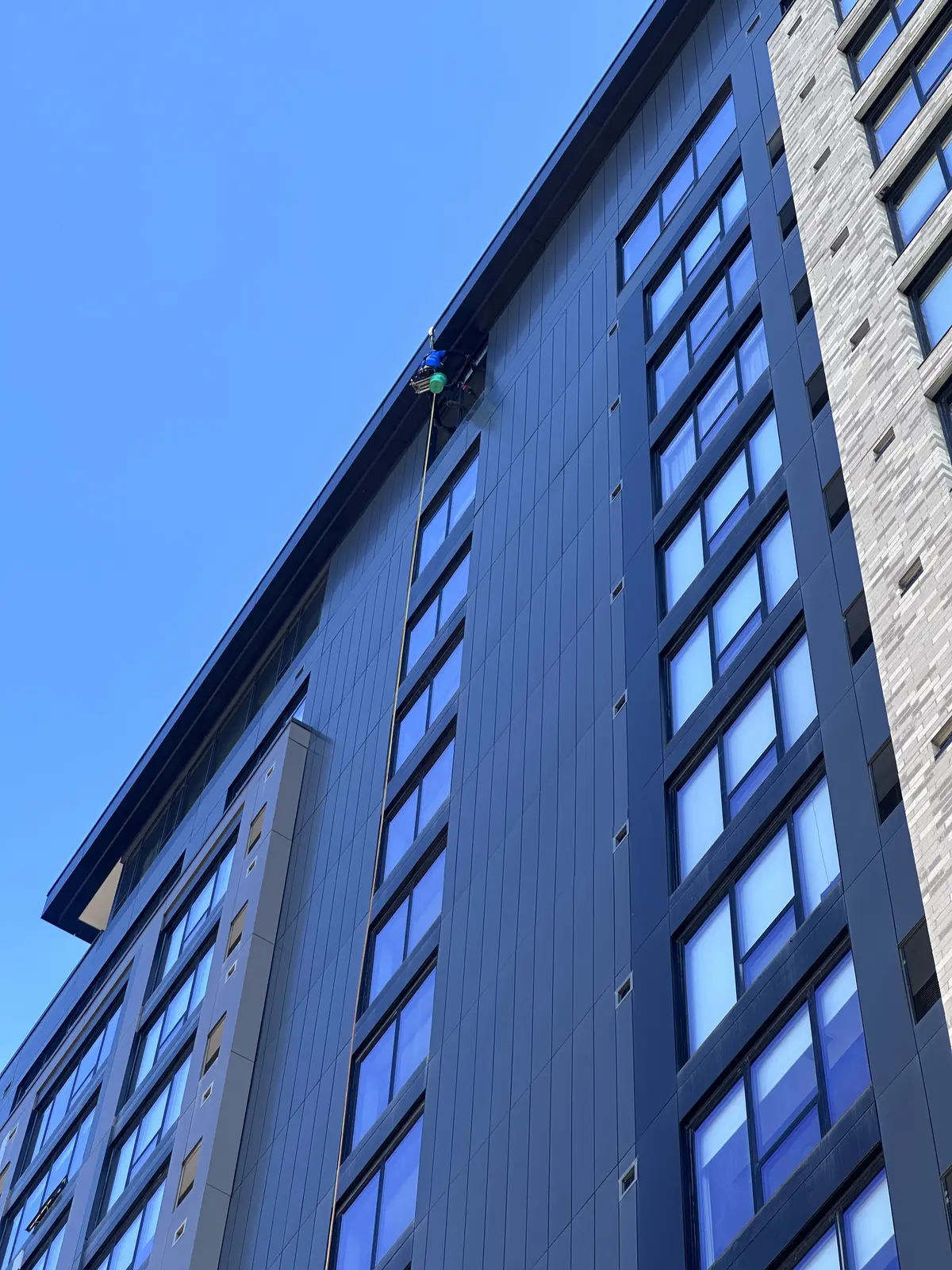 Starbrite rope-access technician descending from the roof to clean windows on The Larking, a 20-plus story apartment tower in downtown Minneapolis