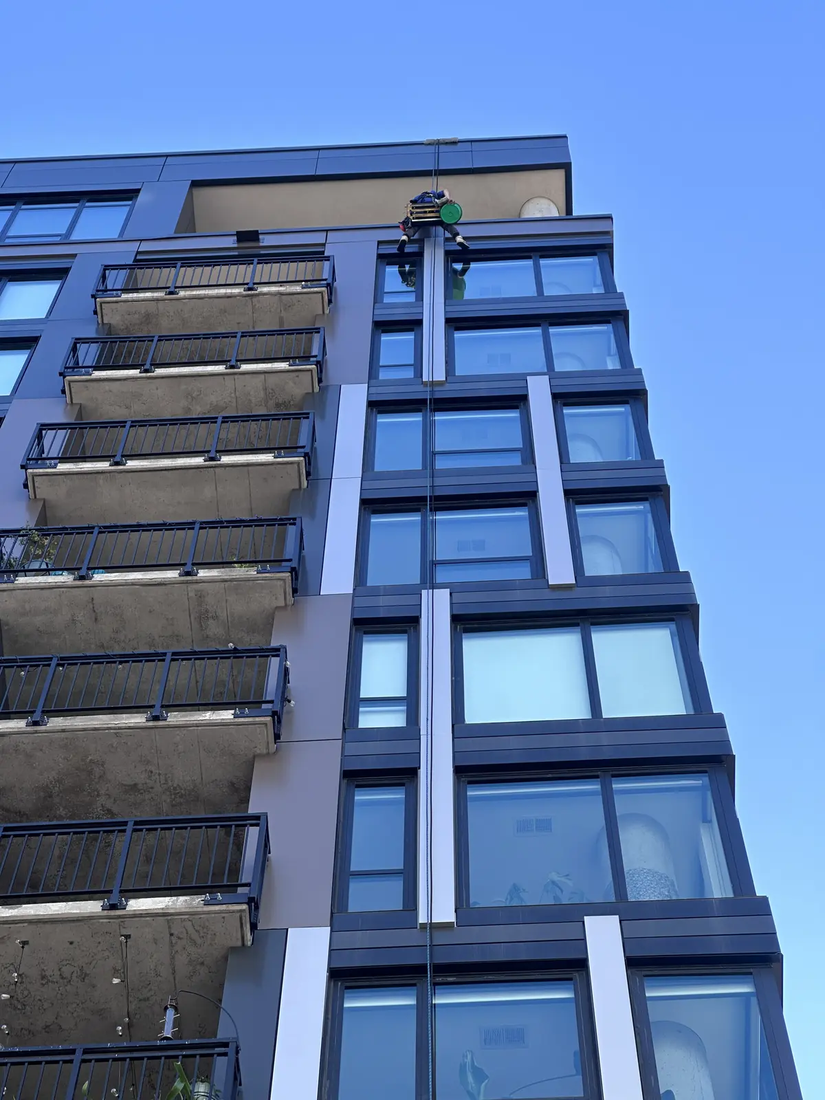 Starbrite window cleaning technician rappelling down the glass and balconies of The Larking high-rise in downtown Minneapolis