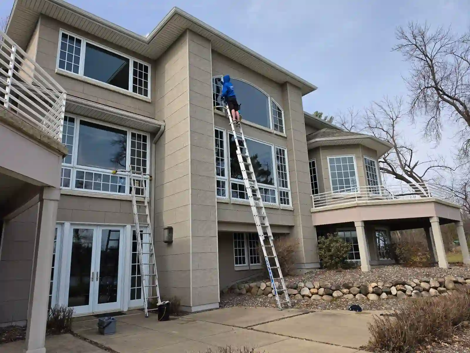 Starbrite crew on extension ladders cleaning upper-story windows on a three-story Minnesota home