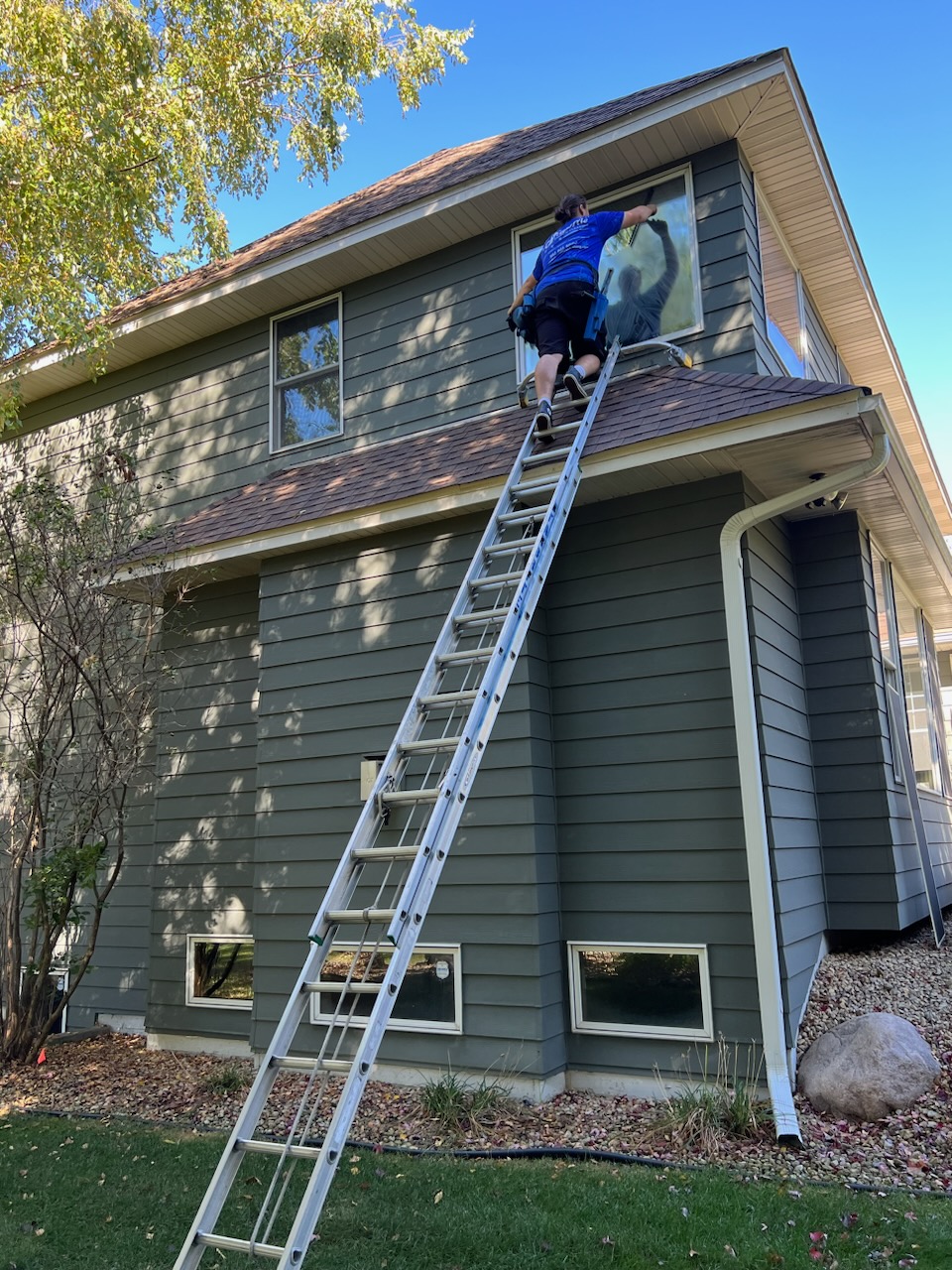 Starbrite technician cleaning upper-story exterior windows on a two-story home