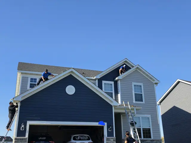 Christmas light installers on the roof and ladder at a Blaine, MN home