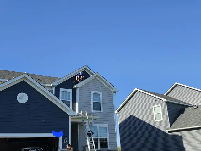 Starbrite technician clipping holiday lights along a roof peak in Blaine, Minnesota