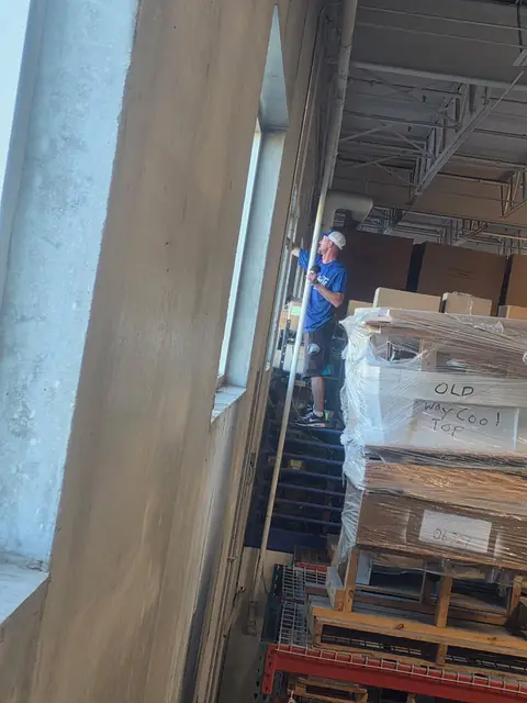 Starbrite technician cleaning tall interior warehouse windows at a Brooklyn Park, MN business