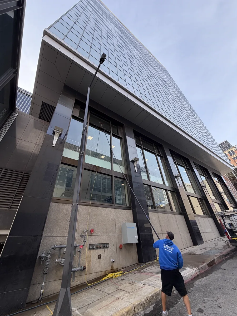 Starbrite Window Cleaning technician using a water-fed pole to clean storefront and second-story windows on an office tower in downtown St. Paul, Minnesota