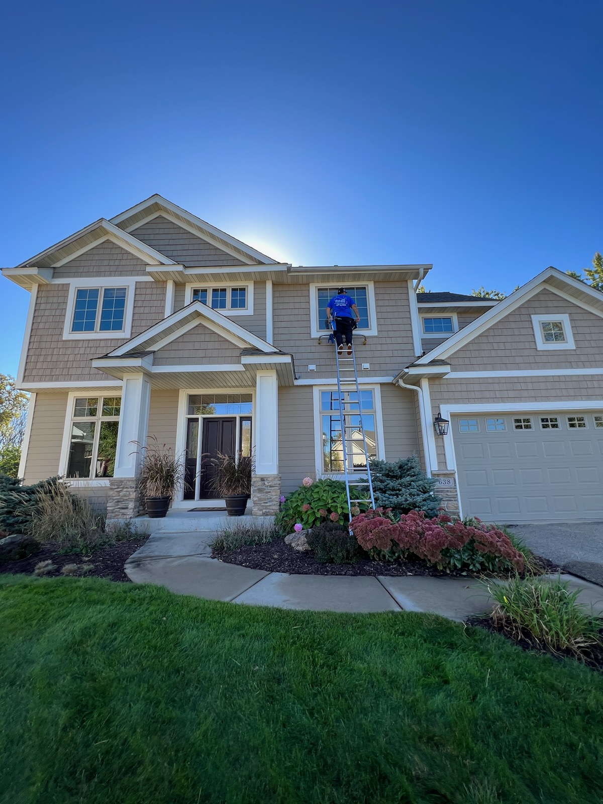 Starbrite technician cleaning exterior windows on a large two-story Twin Cities home